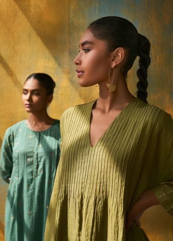 Two women in the Paddmmaja collection, photographed against a hand-painted gold wall